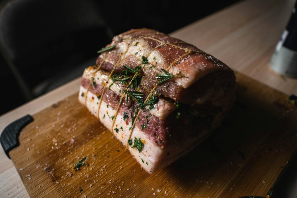 Preparazione di carne di maiale con aromi, fotografia illustrativa della ricetta dell'arista al forno